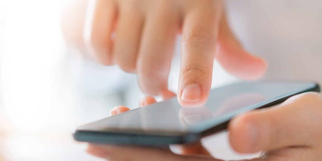 Dedo acercándose a la pantalla de un celular para tocarla